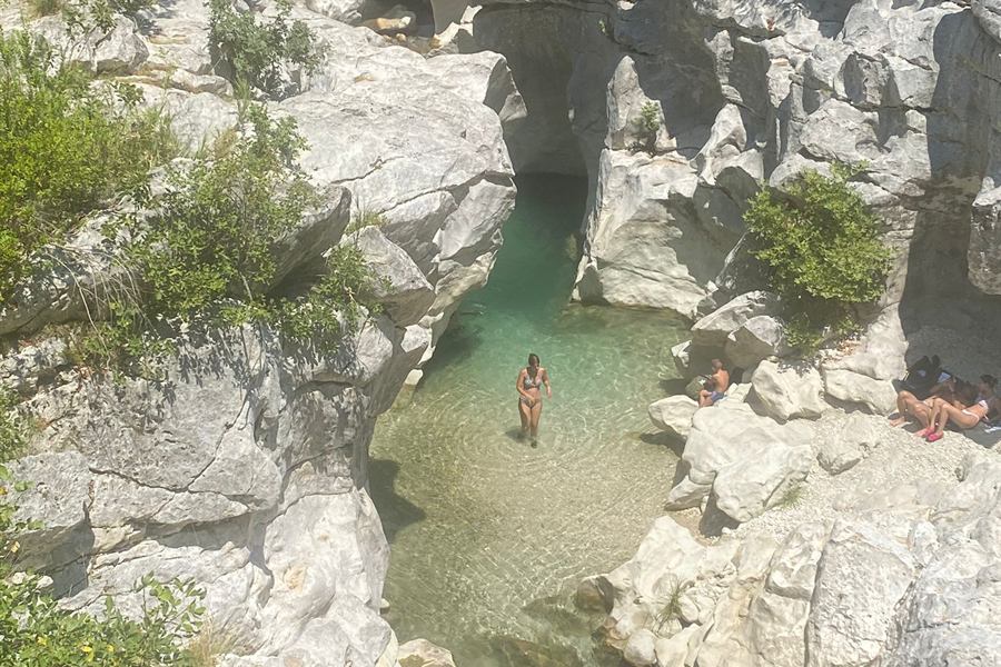 Emerald pool and cave at the Acheron springs, a swimmer wading in